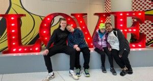 L’Arche Assistants and Members seated in front of the word LOVE L'Arche Assistants and Members seated in front of the word LOVE