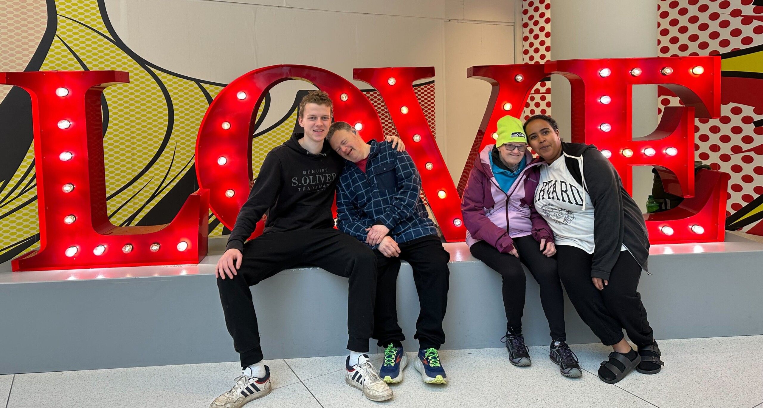 L’Arche Assistants and Members seated in front of the word LOVE L'Arche Assistants and Members seated in front of the word LOVE
