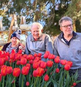 L’Arche Members behind a bed of red tulips